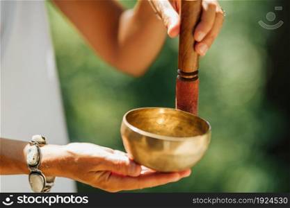 Hands holding Tibetan singing bowl outdoors, playing calming sounds. Hands Holding Tibetan Singing Bowl Outdoors