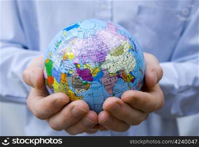 Hands holdings a globe on a blue