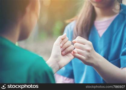 hands hook each other's little finger on nature background, concept of promise