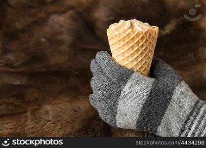 Hands in knitted gloves keep ice cream