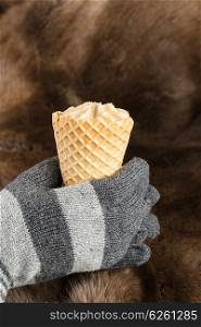 Hands in knitted gloves keep ice cream