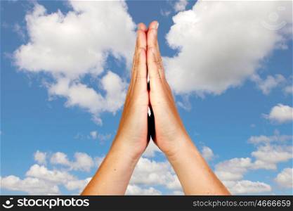 Hands in prayer position against a beautiful sky background