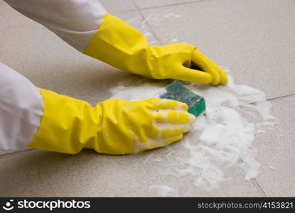 Hands in yellow gloves with sponge, washing floor