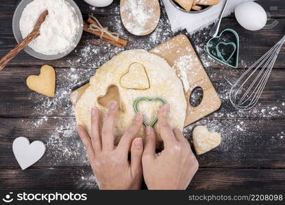 hands making valentines day heart shaped cookies with kitchen utensils