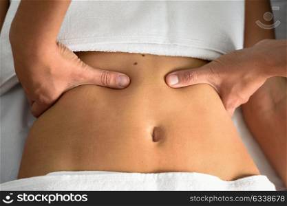Hands massaging female abdomen.Therapist applying pressure on belly. Woman receiving massage at spa salon