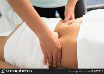 Hands massaging female abdomen.Therapist applying pressure on belly. Woman receiving massage at spa salon
