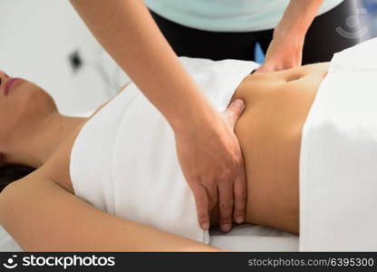 Hands massaging female abdomen.Therapist applying pressure on belly. Woman receiving massage at spa salon