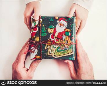 Hands of a child and an adult male, bright, colorful gift boxes. Merry Christmas and Happy New Year. Hands of a child and gift boxes