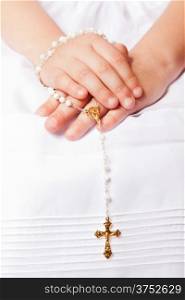 Hands of a little her in the First Communion Day Holding a Golden Cross