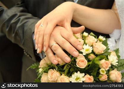 Hands of a newly-married couple. Tenderness of the groom and the bride above wedding a bouquet