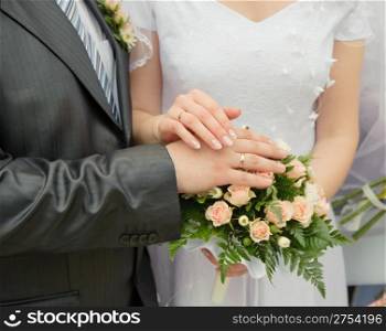 Hands of a newly-married couple. Tenderness of the groom and the bride above wedding a bouquet