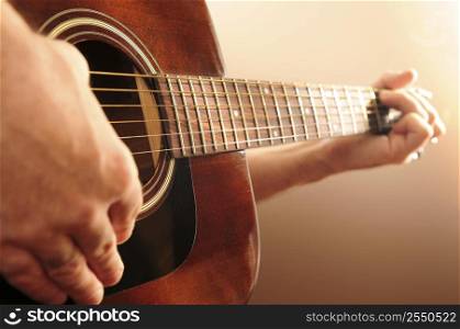 Hands of a person playing an acoustic guitar