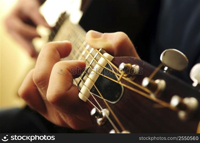 Hands of a person playing an acoustic guitar close up