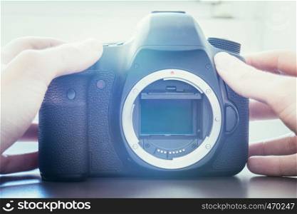 Hands of a photographer are touching a professional reflex camera, open sensor