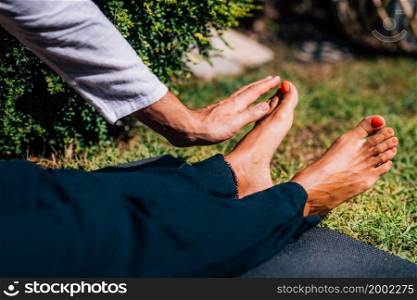Hands of a Reiki therapist healing and balancing energy points in feet. Energy healing concept. Reiki Foot Treatment