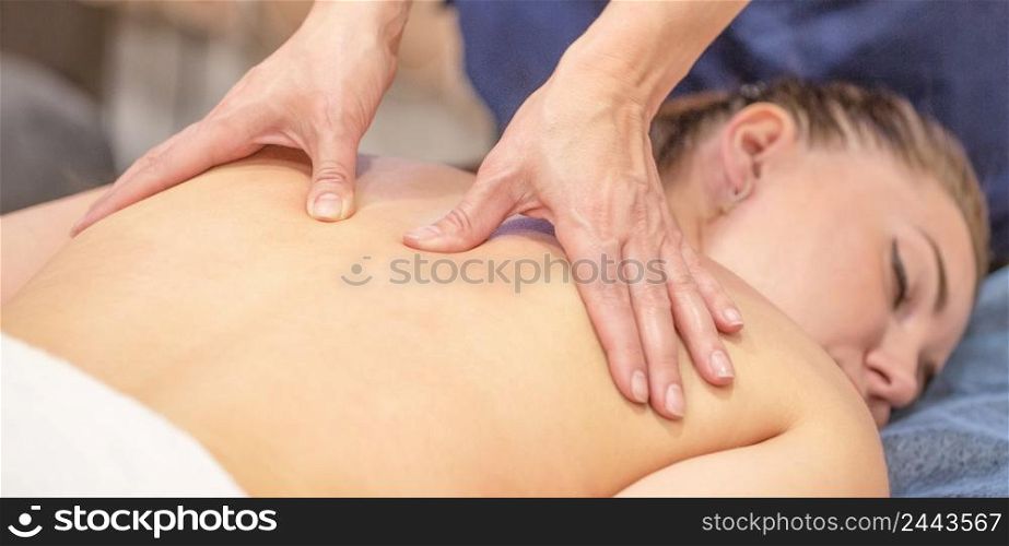 Hands of a woman masseur make therapeutic massage on back of a young girl. Advertising a beauty salon or massage room treatment room. Hands of a woman masseur make therapeutic massage on back of a young girl