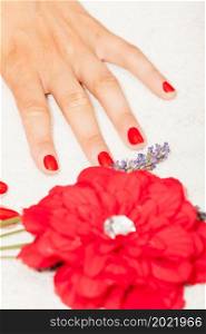 Hands of a woman with red nail polish posed by an esthetician