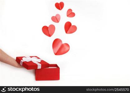 hands of a young man holding a small present box with red hearts on a white background. hands of a young man holding a present box with red hearts on a white background