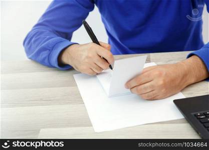 hands of a young man writing on a piece of paper