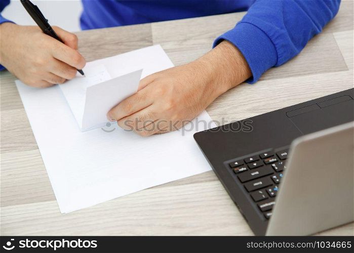 hands of a young man writing on a piece of paper