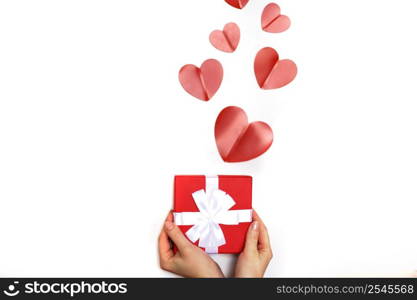 hands of a young woman holding a small present box with red hearts on a white background. hands of a young woman holding a present box with red hearts on a white background