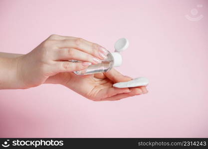 Hands of a young woman with antibacterial liquid. Disinfection and antiseptic on a pink background. Coronavirus prevention, health care.. Hands of a young woman with antibacterial liquid. Disinfection and antiseptic on a pink background. Coronavirus prevention.