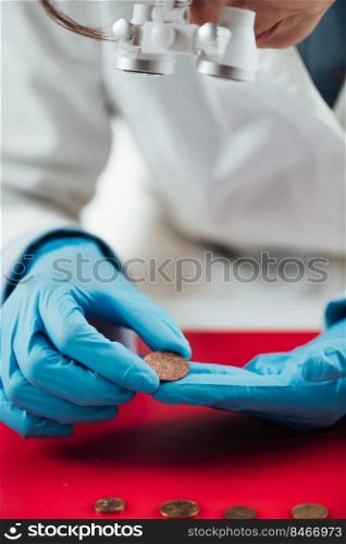 Hands of ancient coins valuation expert researching value of coins. Ancient Coins Valuation