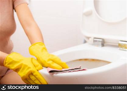 Hands of Asian woman cleaning toilet seat by pink cloth wipe restroom at house, female wearing yellow rubber gloves she sitting and cleanup or washing bathroom, Housekeeper healthcare concept