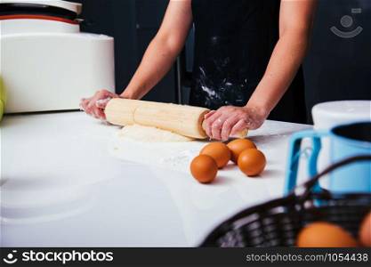 Hands of baker woman female making dough pastry pie with rolling wooden