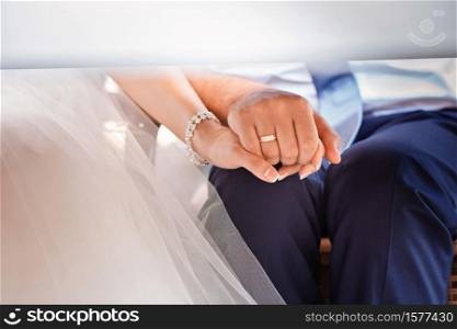Hands of bride and groom in wedding rings under the table