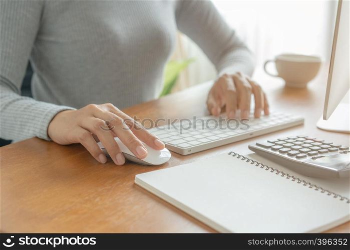 Hands of business woman using keyboard and computer. Asian woman working on desk with calculator, book bank .