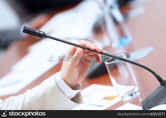 Hands of businessman holding microphone. Image of businessman&rsquo;s hands holding microphone at conference