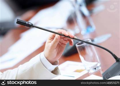 Hands of businessman holding microphone. Image of businessman&rsquo;s hands holding microphone at conference