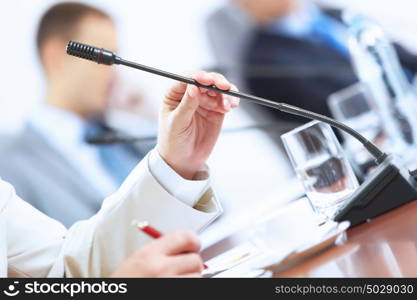 Hands of businessman holding microphone. Image of businessman&rsquo;s hands holding microphone at conference