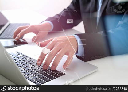 Hands of businessman typing on laptop in modern office with smart phone and digital tablet computer with VR icon diagram