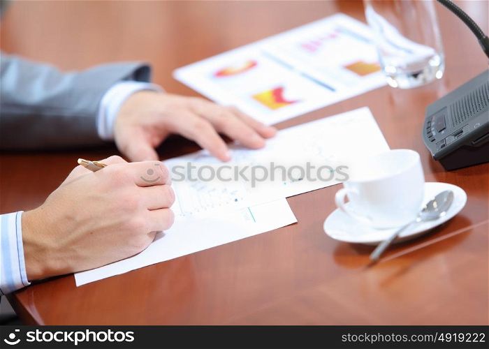 Hands of businessman writing. Image of businessman&rsquo;s hands signing documents at meeting