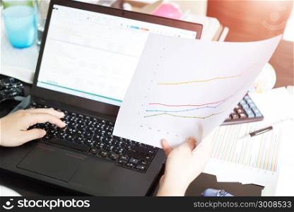 Hands of businesswoman holding analysis chart with laptop and calculator. Accounting.