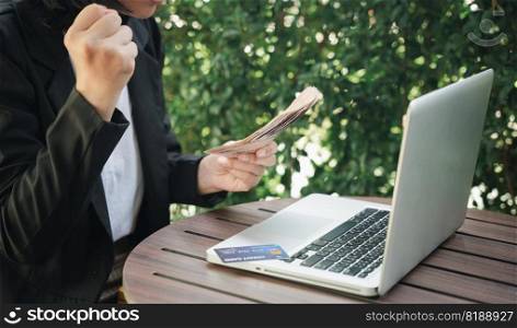Hands of businesswoman holding thai money and credit card on laptop computer, woman using working and shopping, Online e-commerce, internet banking