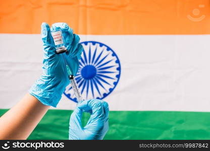 Hands of doctor wear gloves holding coronavirus  COVID-19  vial vaccine and syringe on flag India background, India Vaccination