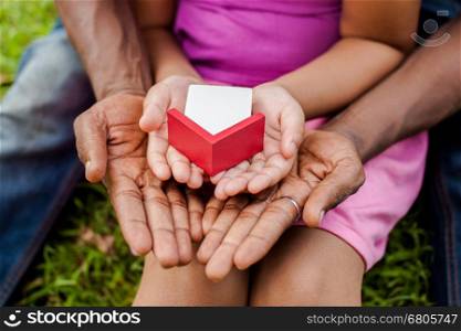 Hands of family together holding house in green park - family home and real estate concept