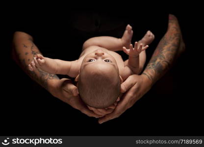 Hands of Father and Mother Hold Newborn Baby Under Dramatic Lighting Against A Black Background.