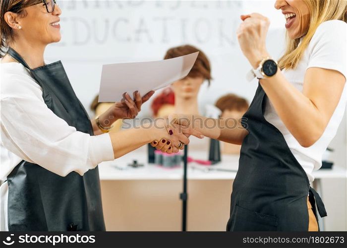 Hands of Hairdressing Educator Giving Hairstylist Certificate to a Student after Successfully Finished Course