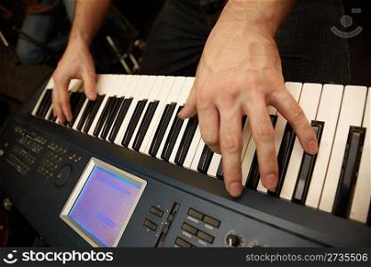 hands of keyboard player on keys of synthesizer. focus on big finger of left hand