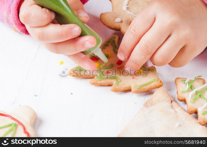 Hands of little girl, who draws on gingerbread cookies