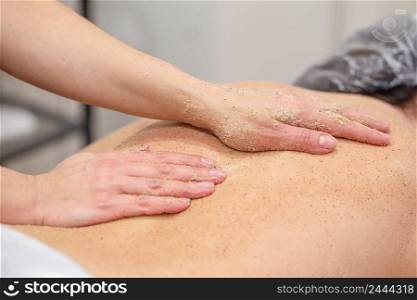 Hands of massagist are scrubbing the woman’s back. Selective focus on the main subject. Hands of massagist are scrubbing woman’s back