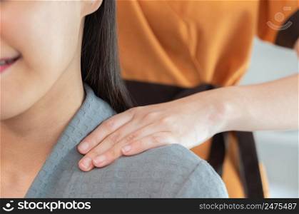 Hands of masseur massaging neck of young smiling woman on massage table