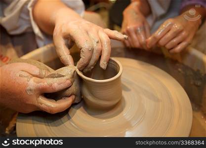 Hands of master creating pot on potter&acute;s wheel. Traditional craft. Focus on the hands.