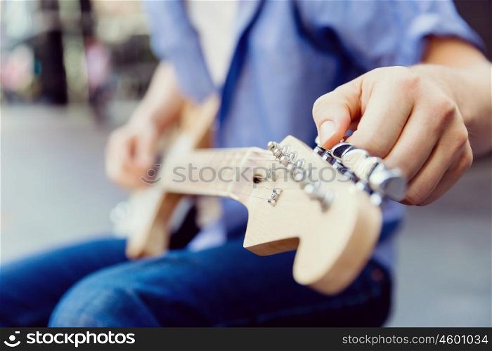 Hands of musician with guitar. Hands of musician tuning his guitar outside