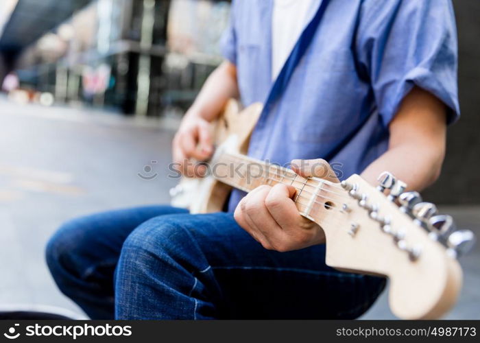 Hands of musician with guitar. Hands of musician tuning his guitar outside