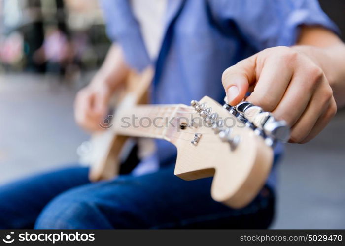 Hands of musician with guitar. Hands of musician tuning his guitar outside